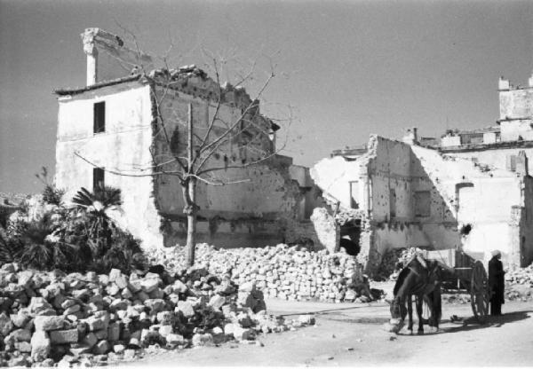 Italia Dopoguerra. Terracina. Edifici distrutti dai bombardamenti. Un uomo con carretto fermo all'incrocio di due strade