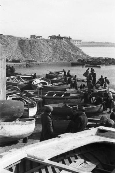 Italia Dopoguerra. Pozzuoli. Piccole imbarcazioni in secca e persone presso il porto