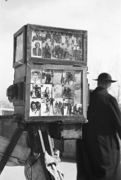 Italia Dopoguerra. Napoli. La macchina fotografica del fotografo ritrattista ambulante. Sullo sfondo un prete