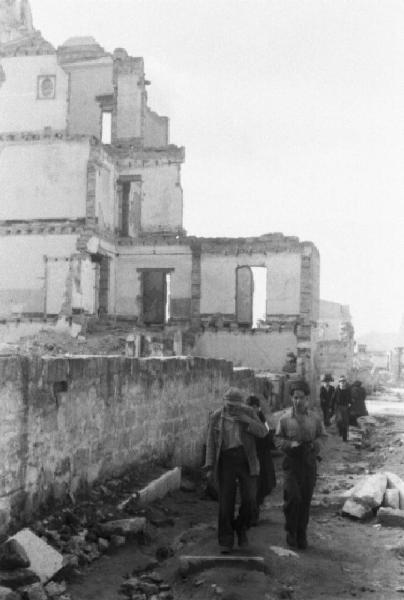 Italia Dopoguerra. Palermo. Giovani camminano a fianco di un edificio distrutto dai bombardamenti