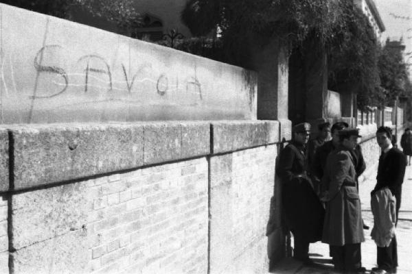 Italia Dopoguerra. Palermo. Gruppo di uomini accanto a un muro con la scritta "SAVOIA"