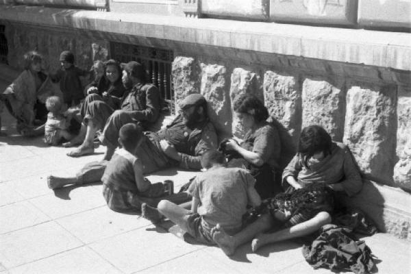 Italia Dopoguerra. Palermo. Famiglie di mendicanti con bambini seduti per terra lungo la strada
