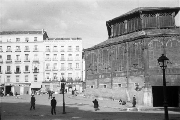 Spagna. Madrid. Piazza con edifici per abitazioni, negozi e costruzione poligonale con ampie persiane in legno