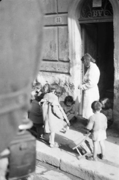 Italia Dopoguerra. Palermo. Bambini giocano sulla soglia di casa, una donna li osserva