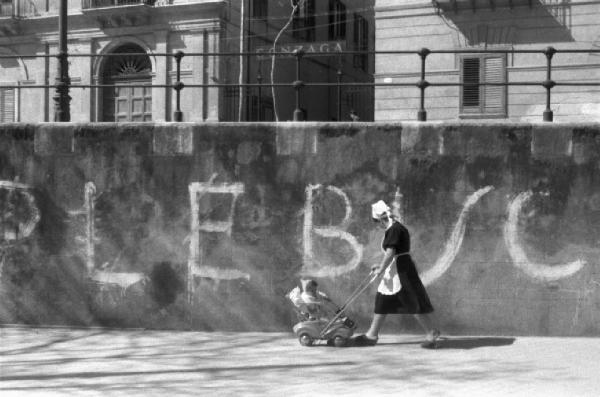 Referendum 1946. Palermo. Una balia con passeggino costeggia un muro con la scritta "PEBLISCITO"