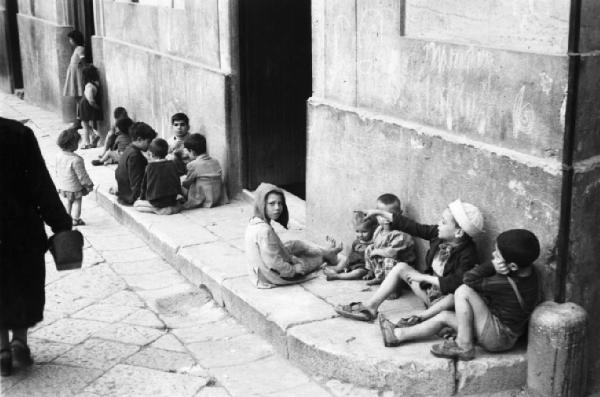 Italia Dopoguerra. Palermo. Bambini seduti per terra giocano lungo la strada