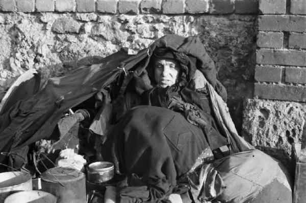 Italia Dopoguerra. Milano. Barbone accovacciato per terra lungo la via Massena