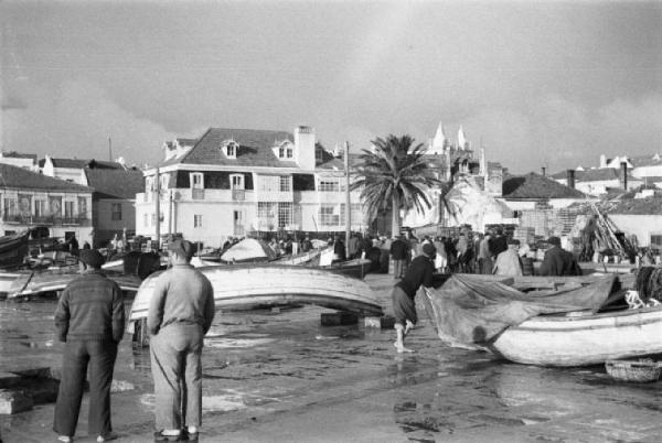 Portogallo. Cascais. Nei pressi del porto. Barche in secca - pescatori e gente del paese radunata sullo spiazzo - sullo sfondo edifici del paese