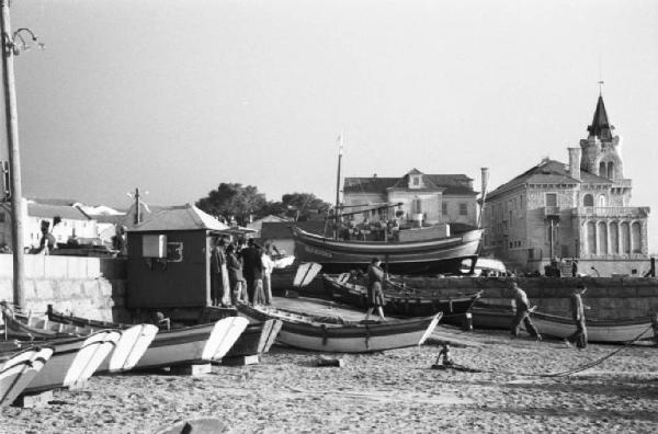 Portogallo. Cascais. Spiaggia con barche in secca e cabina - sullo sfondo edifici del paese