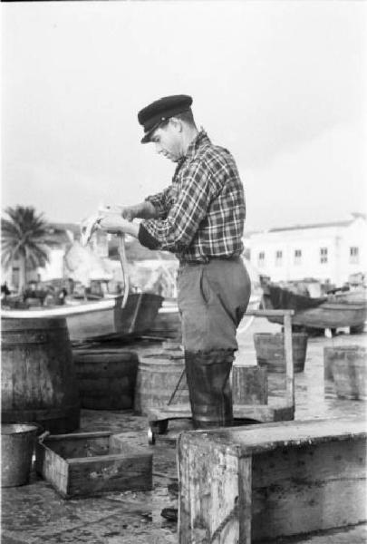 Portogallo. Cascais. Nei pressi del porto. Pescatore pulisce del pesce