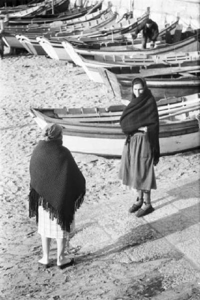 Portogallo. Cascais. Due anziane sulla spiaggia - sullo sfondo alcune barche in secca