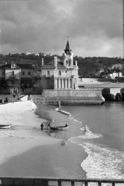 Portogallo. Cascais. Spiaggia con le barche dei pescatori - sullo sfondo gli edifici del paese