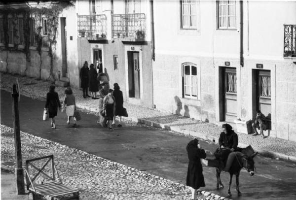 Portogallo. Cascais. Donne passeggiano per le strade del paese - una di esse su un asino