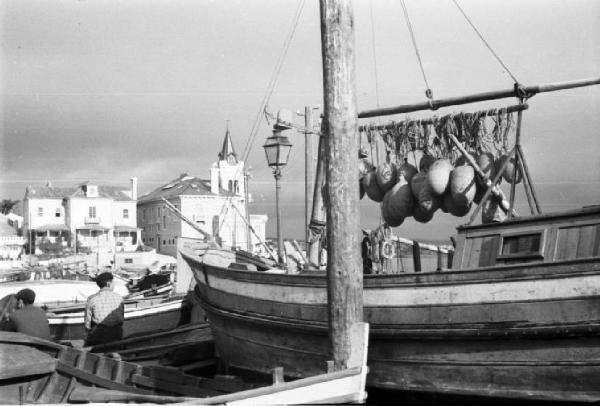 Portogallo. Cascais. Barche dei pescatori con galleggianti appesi - sullo sfondo gli edifici del paese