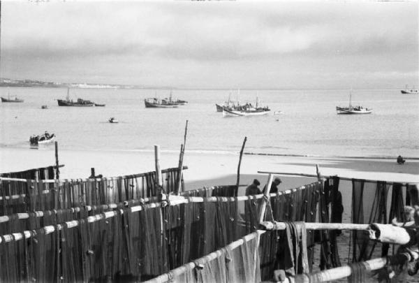 Portogallo. Cascais. Reti dei pescatori sulla spiaggia - sullo sfondo barche nell'oceano