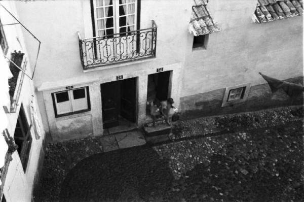 Portogallo. Lisbona. Vicolo della città vecchia - un balcone e due porte di abitazione - da una di esse escono due bambini