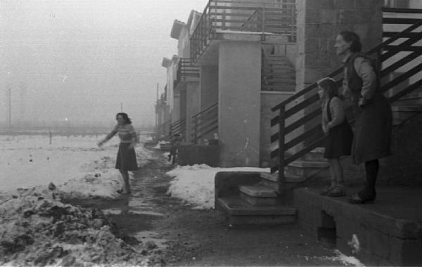 Donne all'ingresso di un edificio. Campi innevati