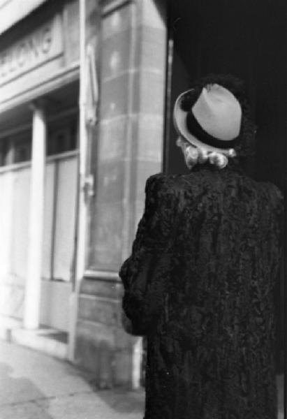 Parigi. Una donna con pelliccia di astrakan e cappello passeggia lungo una via