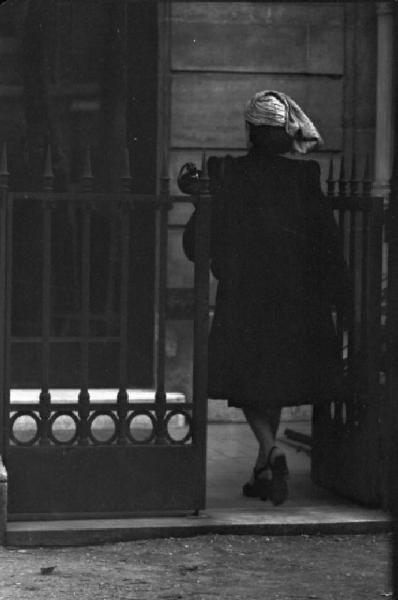 Parigi. Una donna con pelliccia di astrakan e cappello varca un cancello