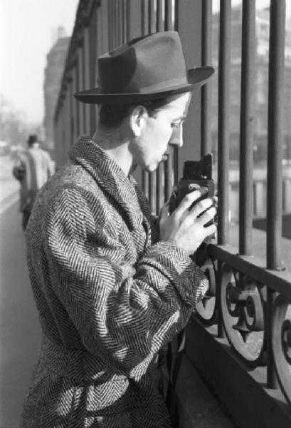 Parigi. Un uomo con macchina fotografica reflex scatta una foto attraverso le inferriate di una cancellata