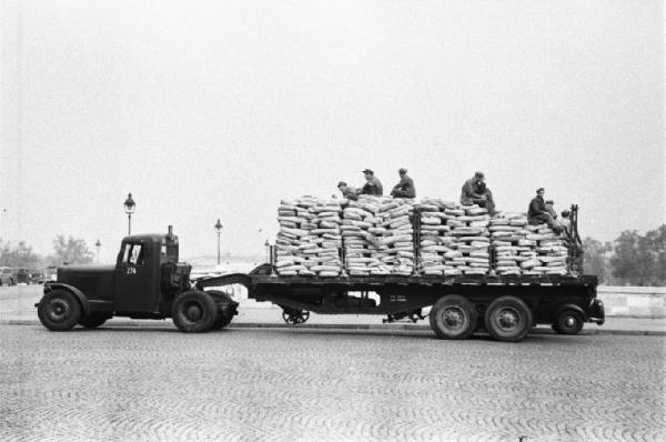 Parigi. Operai seduti su un camion che trasporta sacchi di cemento