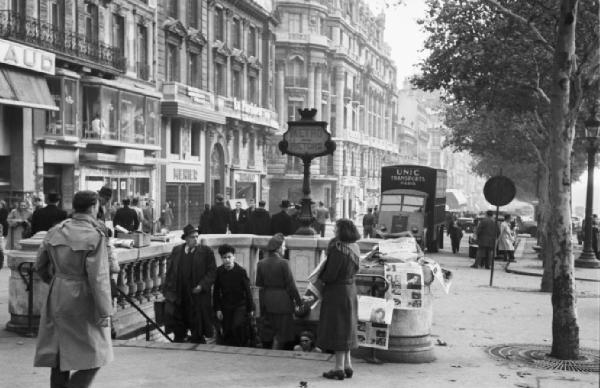 Parigi. Vita quotidiana lungo un viale alberato con fermata della metropolitana