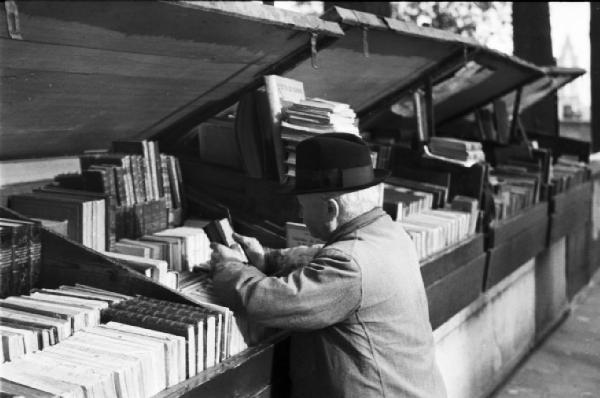 Parigi. Un uomo intento a guardare dei libri presso una libreria lungo la Senna