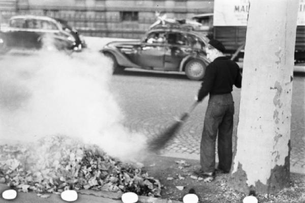 Parigi. Un uomo spazza le foglie secche lungo un viale della città
