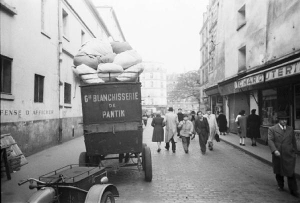 Parigi. Carretto motorizzato ritira la biancheria. Persone camminano lungo la strada