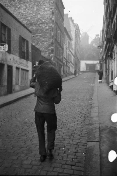 Parigi. Il quartiere di Montmartre. Un uomo porta in spalla un sacco