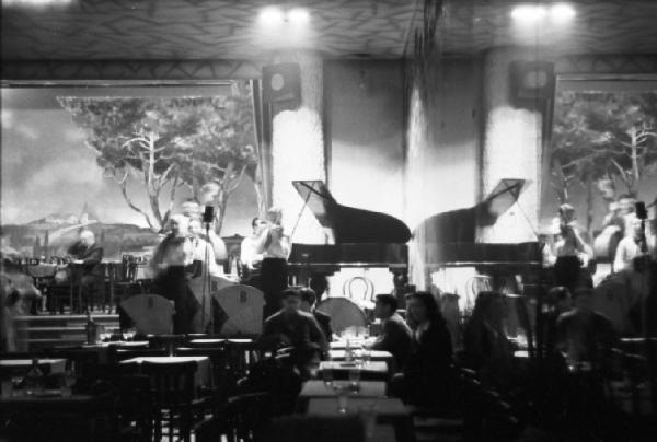 Parigi. Interni del locale Moulin Rouge. Clienti seduti ai tavoli mentre l'orchestra suona