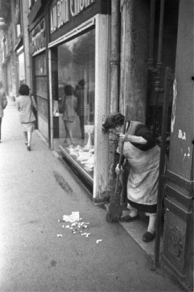 Parigi. Una donna spazza l'uscio di un portone