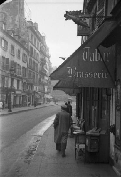 Parigi. Scorcio di una via. Dei passanti e una brasserie