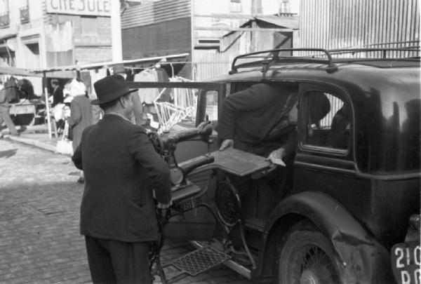 Le Vésinet. Il mercato delle pulci. Due uomini caricano una macchina da cucire su un'automobile