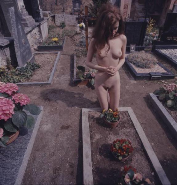 Nudo femminile in ginocchio davanti a una tomba all'interno di un cimitero