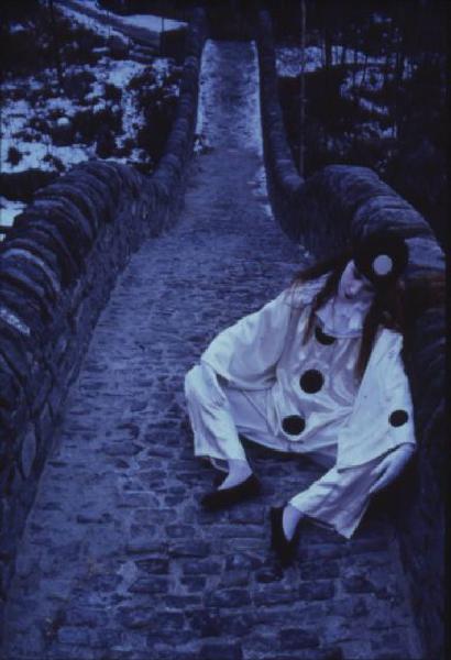 Ragazza in abito da Pierrot sdraiata sopra un ponte