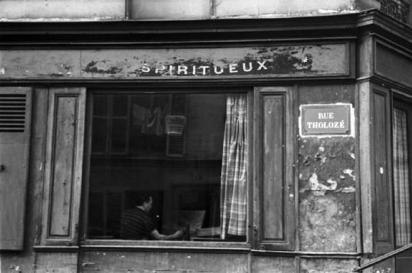 Parigi. Esterno del locale La baite de "La Pomme" a Montmartre. Artista al lavoro ritratto atrraverso la finestra aperta che dà sulla strada