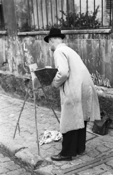 Parigi. Pittore al lavoro in una via di Montmartre