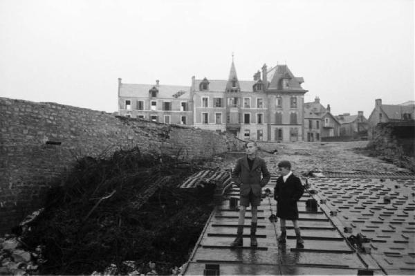 Normandia. Arromanches. Due bambini ritratti sopra un ponte in ferro e una residenza nobiliare sullo sfondo