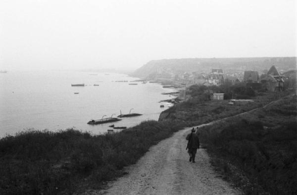 Normandia. Arromanches. Le spiagge teatro dello sbarco alleato. La strada costiera  che conduce al paese e rottami di mezzi anfibi affioranti dal mare