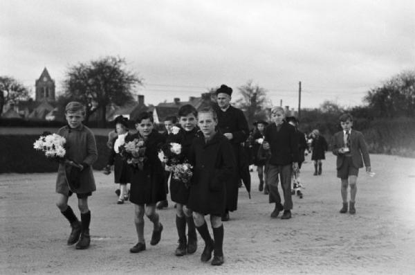 Normandia. St. Mère Eglise, i bambini del paese e il parroco si recano a una commemorazione religiosa in memoria dello sbarco alleato