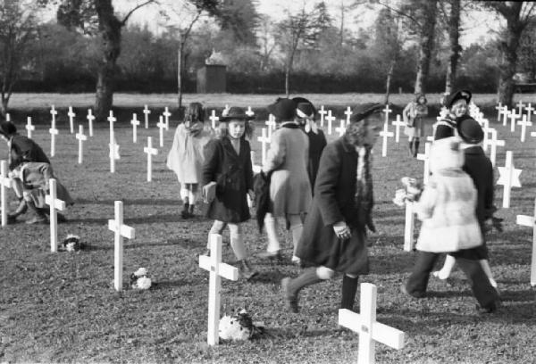 Normandia. St. Mère Eglise, cimitero di guerra. I bambini del paese recano fiori alle croci in occasione di una commemorazione religiosa in memoria dei caduti dello sbarco alleato