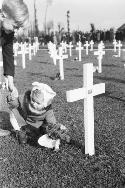 Normandia. St. Mère Eglise, cimitero di guerra. Due bambini del paese recano fiori a una croce in occasione di una commemorazione religiosa in memoria dei caduti dello sbarco alleato