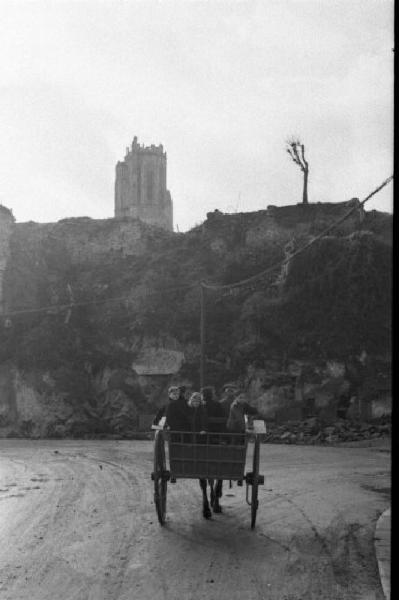 Normandia. St. Mère Eglise. Abitanti del paese in carrozza si recano alla commemorazione religiosa in memoria dei caduti dello sbarco alleato. Sullo sfondo le rovine di una chiesa