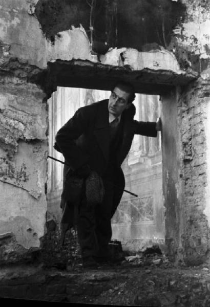 Italia Dopoguerra. Ritratto maschile, il pittore e architetto Fabrizio Clericisi posa tra le rovine di un palazzo bombardato