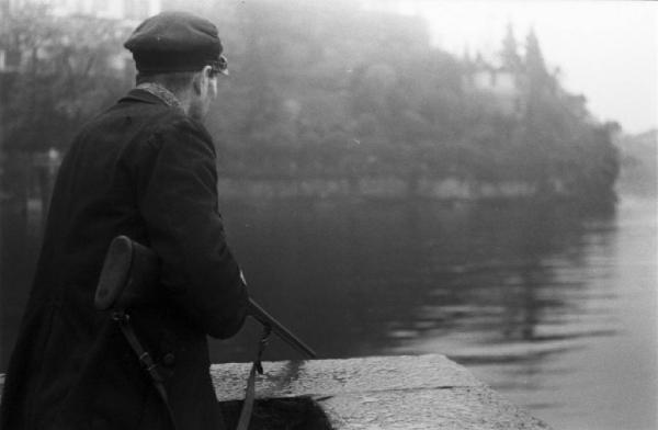 Il mostro del lago di Como. Uomo con fucile puntato verso le acque del lago