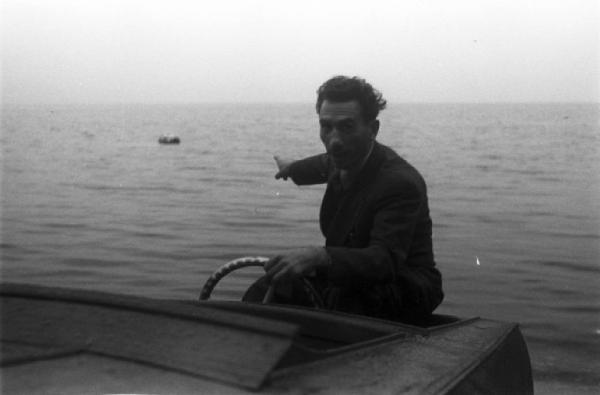 Il mostro del lago di Como. Ritratto maschile, uomo, a bordo di una imbarcazione a motore, indica le acque del lago
