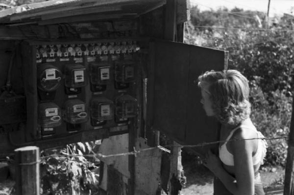 Italia Dopoguerra. Milano - Periferia - Baraccopoli - Norma Barbieri osservai contatori dell'elettricità