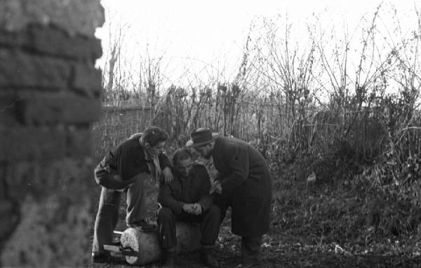 Gruppo di partigiani nei pressi di una abitazione tra la vegetazione