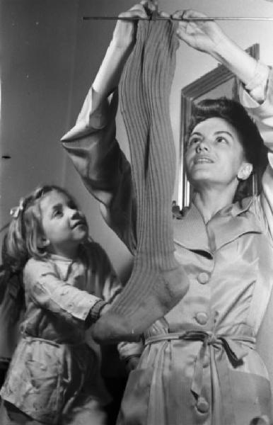 Madre con la calza per i doni della befana sotto lo sguardo della figlia